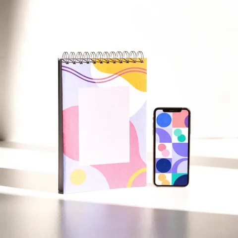 La Guía Vendé Tus Diseños junto al catálogo en el celular